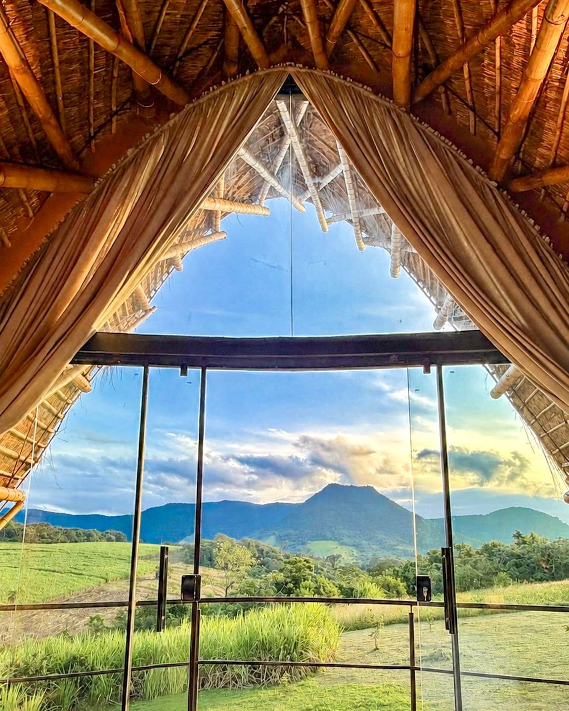 El arco de la bóveda de tacuara enmarcando el Cerro Amor a través del vidrio, con el campo abierto delante.