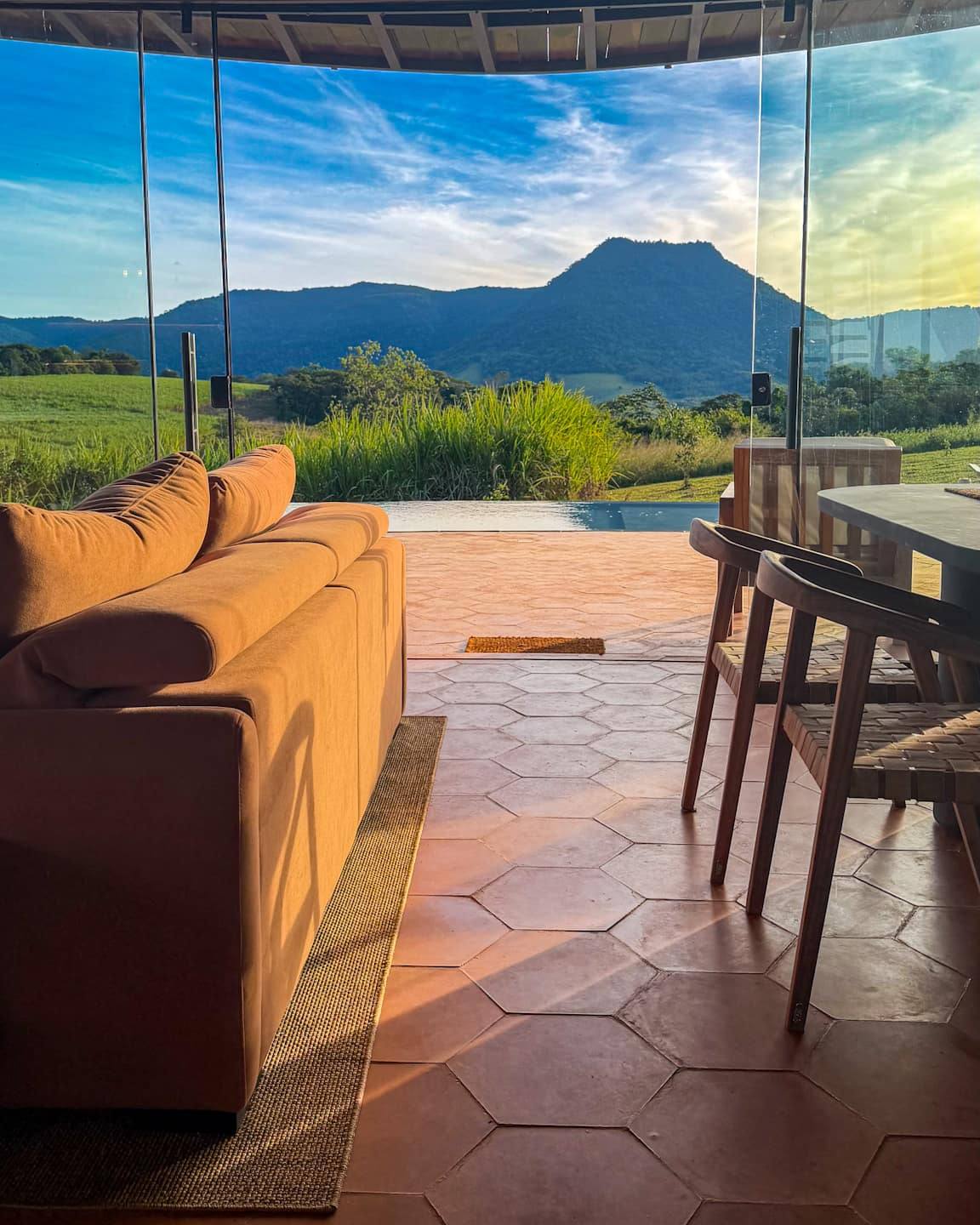 El living abierto a la terraza: el sofá, la mesa, la piscina y el Cerro Amor del otro lado del vidrio.